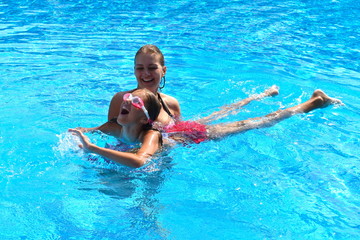 Fototapeta na wymiar Mother and daughter having fun by the pool. Happy parenthood. The mother and daughter at a hotel in the tropics