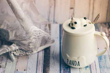A white mug with a panda figurine and the words "panda" on wooden background
