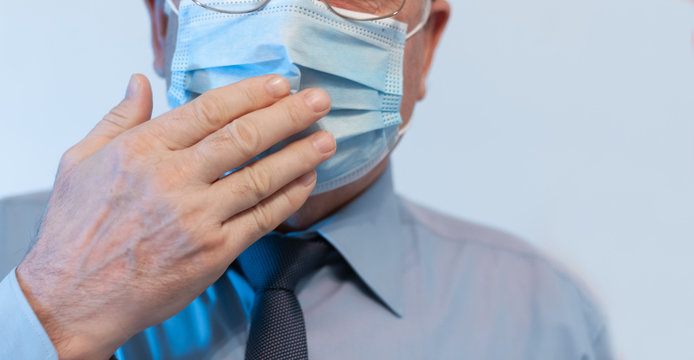 Coronavirus quarantine and Air pollution pm2.5 concept. Old sick man wearing respirator mask for protect holds hands near the face. Wuhan, China epidemic virus symptoms background.