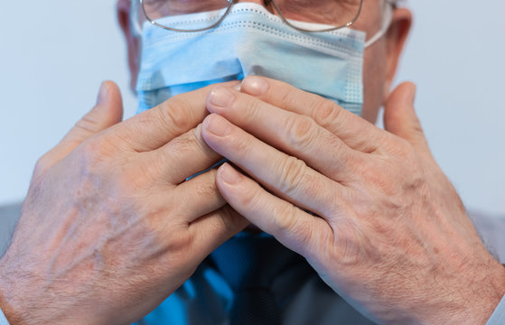 Coronavirus quarantine and Air pollution pm2.5 concept. Old sick man wearing respirator mask for protect holds hands near the face. Wuhan, China epidemic virus symptoms background.