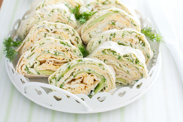 Spring pita roll with fresh cucumber, egg and cheese on a white dish with fresh herbs, horizontal