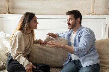 Happy millennial couple talk relaxing in living room