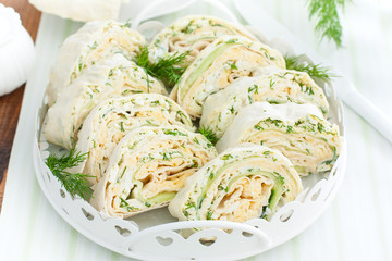 Spring pita roll with fresh cucumber, egg and cheese on a white dish with fresh herbs, horizontal