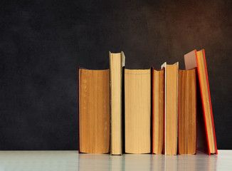 Back to school, pile of books with empty black school board background, education concept.