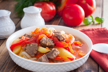 Khashlama with beef and vegetables on a wooden table, selective focus