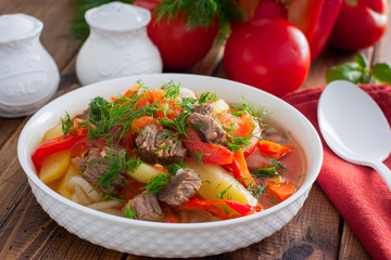 Khashlama with beef and vegetables on a wooden table, selective focus