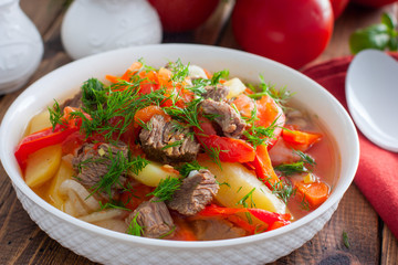 Khashlama with beef and vegetables on a wooden table, selective focus