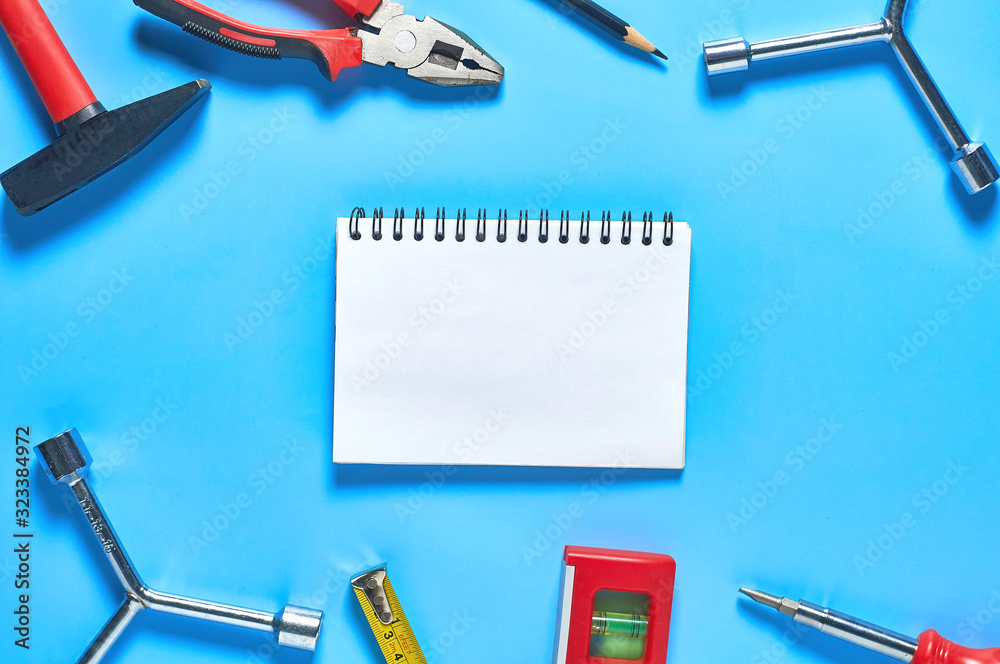 Wall mural different tools lies near blank paper notebook on blue desk in workshop. space for text. top view