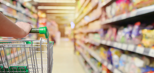 shopping cart in supermarket aisle with product shelves interior defocused blur background