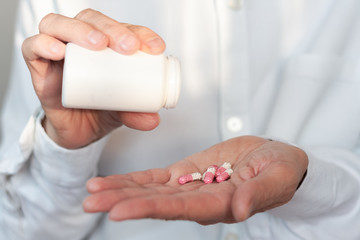 Female hand close up holding a medicine, elderly woman hands with pill on spilling pills out of bottle .