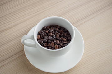 fresh roasted coffee beans in white cup on wood table
