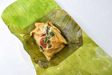 Thai Steamed Curried Fish in banana leaf placed on a white dish.