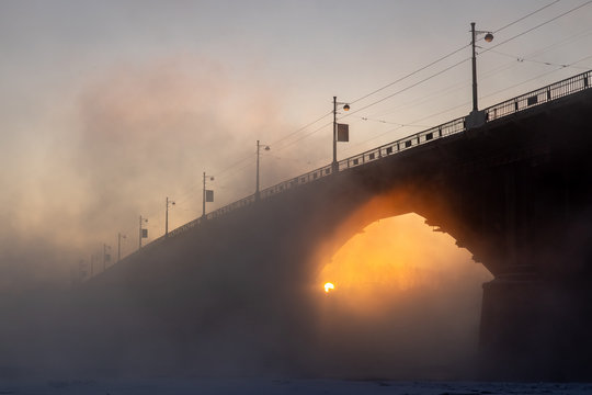 The sun rises in the arch of the bridge over the Angara