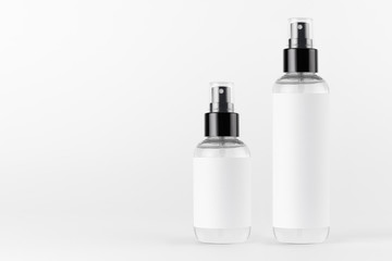 Tall, low transparent spray dispenser bottle for cosmetics with white label on white background,...