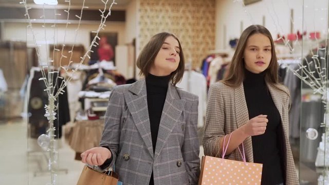 girls leave the store in a shopping mall with packages