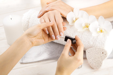 beautiful french manicure with orchid, candle and towel on the white wooden table. manicurist hands