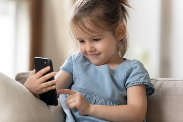 Adorable little preschool kid girl using smartphone.