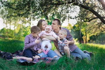 Fototapeta premium Family having a great time outdoors. Mom, dad and three children. Father kissing daughter