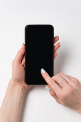 Female hands holding phone and point your finger at the screen. Black display, white background. Vertical frame