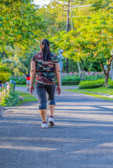 A man and a  woman are jogging in the evening on the public park