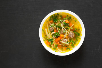 Homemade Sopa a La Minuta in a white bowl on a black surface, top view. Copy space.