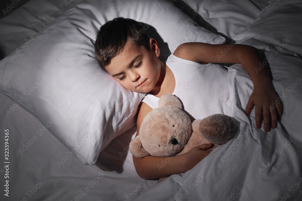 Wall mural little boy sleeping with teddy bear at home. bedtime