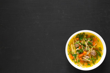 Homemade Sopa a La Minuta in a white bowl on a black surface, top view. Copy space.