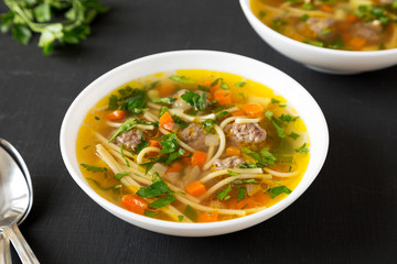 Homemade Sopa a La Minuta in white bowls on a black background, low angle view. Close-up.