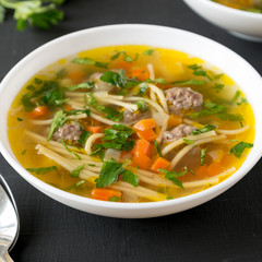 Homemade Sopa a La Minuta in white bowls on a black surface, low angle view. Close-up.