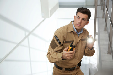 Fototapeta na wymiar Professional security guard with portable radio set and flashlight on stairs