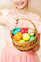 Little girl holding a basket whith handmade painted easter eggs