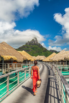 Luxury hotel vacation Tahiti resort travel honeymoon destination tourist woman walking on boardwalk to overwater bungalows villa suite in Bora Bora, French Polynesia.