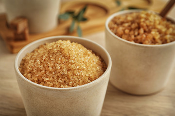 Brown sugar in bowl on wooden table, closeup
