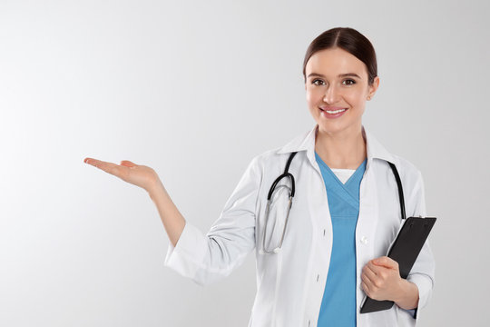 Doctor with stethoscope and clipboard on light grey background