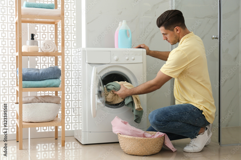 Sticker Man putting clothes into washing machine in bathroom. Laundry day