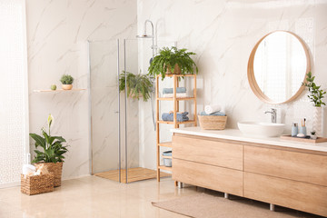 Stylish bathroom interior with countertop, shower stall and houseplants. Design idea