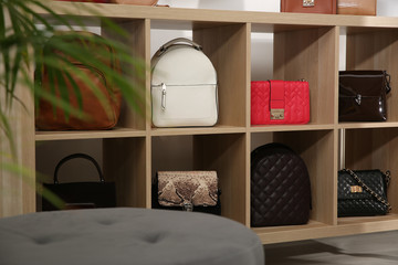 Collection of stylish woman's bags on wooden shelving unit