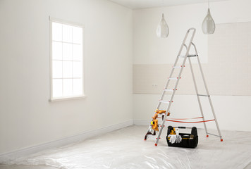 Stepladder and different tools near wall in room. Interior renovation