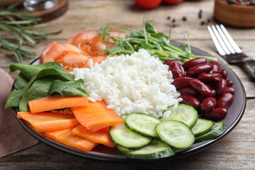 Tasty rice with beans and vegetables on wooden table, closeup