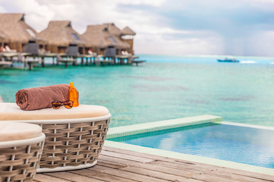Luxury Bora Bora overwater bungalow villas high end hotel in Tahiti, French Polyneisa. Ocean view summer travel destination resort background, sun lounger with towel , sunscreen and sunglasses.