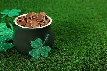 Pot of gold coins and clover leaves on green grass, space for text. St. Patrick's Day celebration