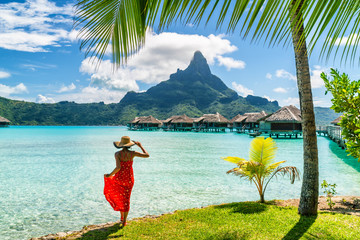 Tahiti travel holiday luxury hotel vacation tourist woman walking on Bora Bora island beach with view of Mt Otemanu in French Polynesia. High end resort with overwater bungalows villas. - obrazy, fototapety, plakaty