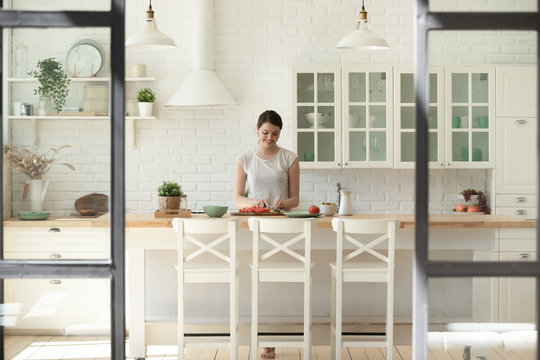 Happy young woman cooking in white modern home kitchen - Powered by Adobe