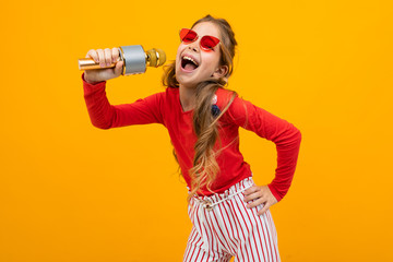 cute european girl singing into a microphone on a yellow background