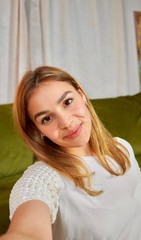 Beautiful healthy smiling mixed race female taking selfie at home.