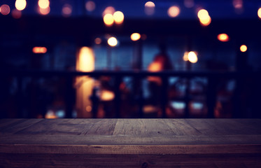 background Image of wooden table in front of abstract blurred restaurant lights