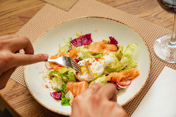 man eating salad with salmon and poached egg