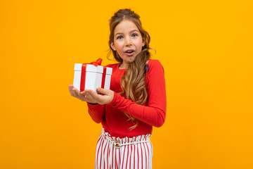 surprised girl with a gift box on a yellow background with copy space