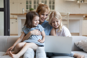 Happy mother relax with daughters using laptop at home