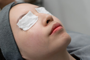 Cosmetologist puts a bandage on the face. preparation face skin before applying a rejuvenating mask in a beauty salon.